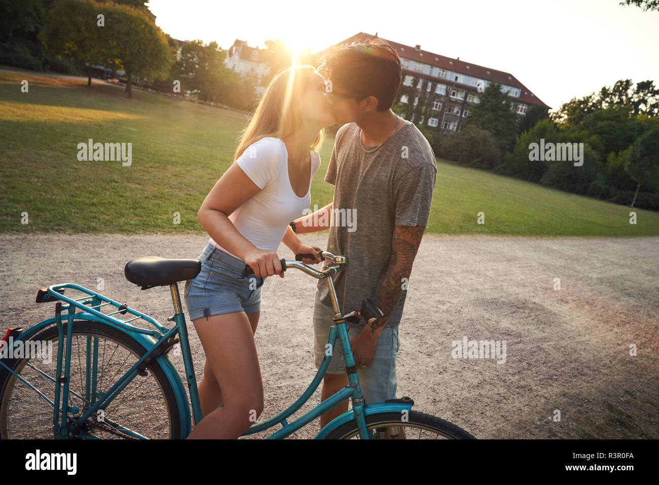 Jeune femme avec son petit ami embrasser, vélos en stationnement Banque D'Images
