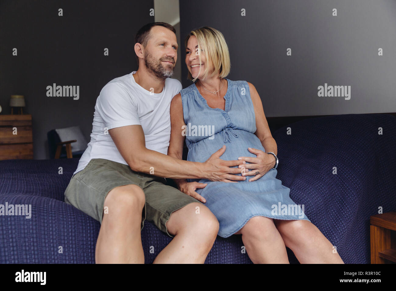 Homme mûr et sa femme mature enceinte sitting on bed touching her belly  Photo Stock - Alamy