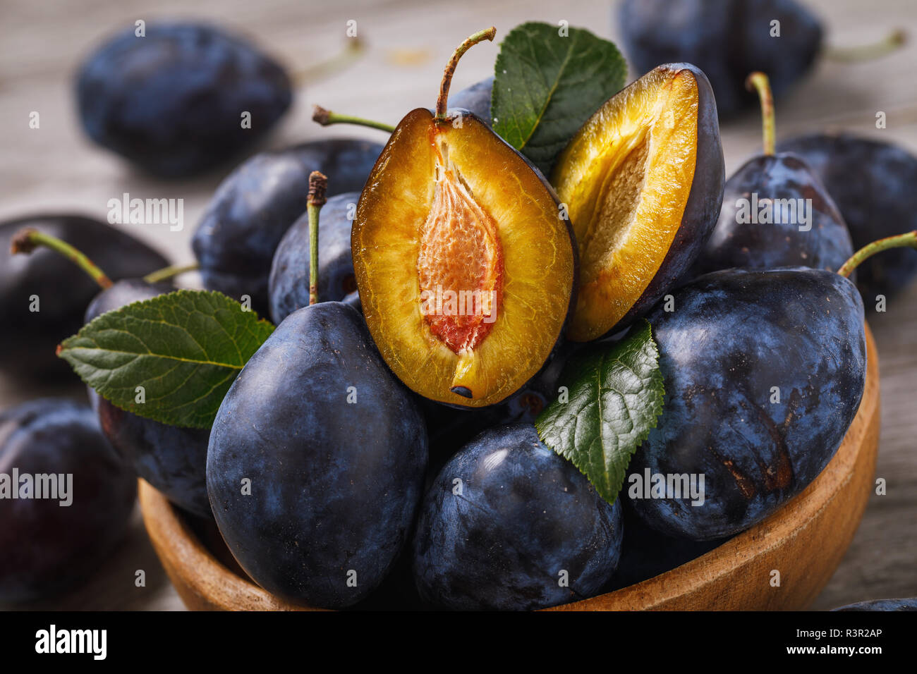 Bol plein de pruneaux mûrs fruits sur une table en bois, gros plan Banque D'Images