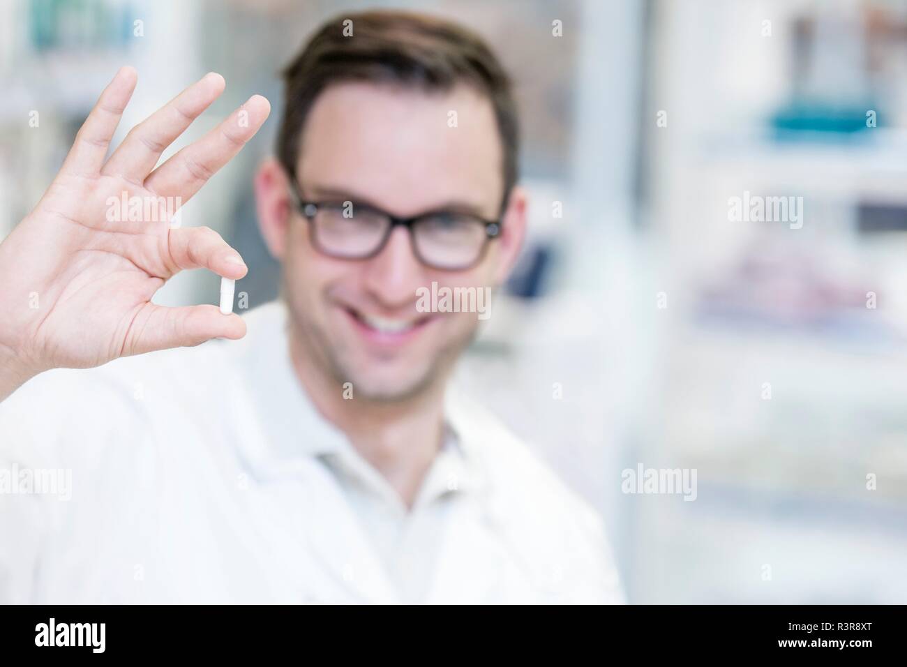 Portrait of smiling pharmacien holding pill. Banque D'Images