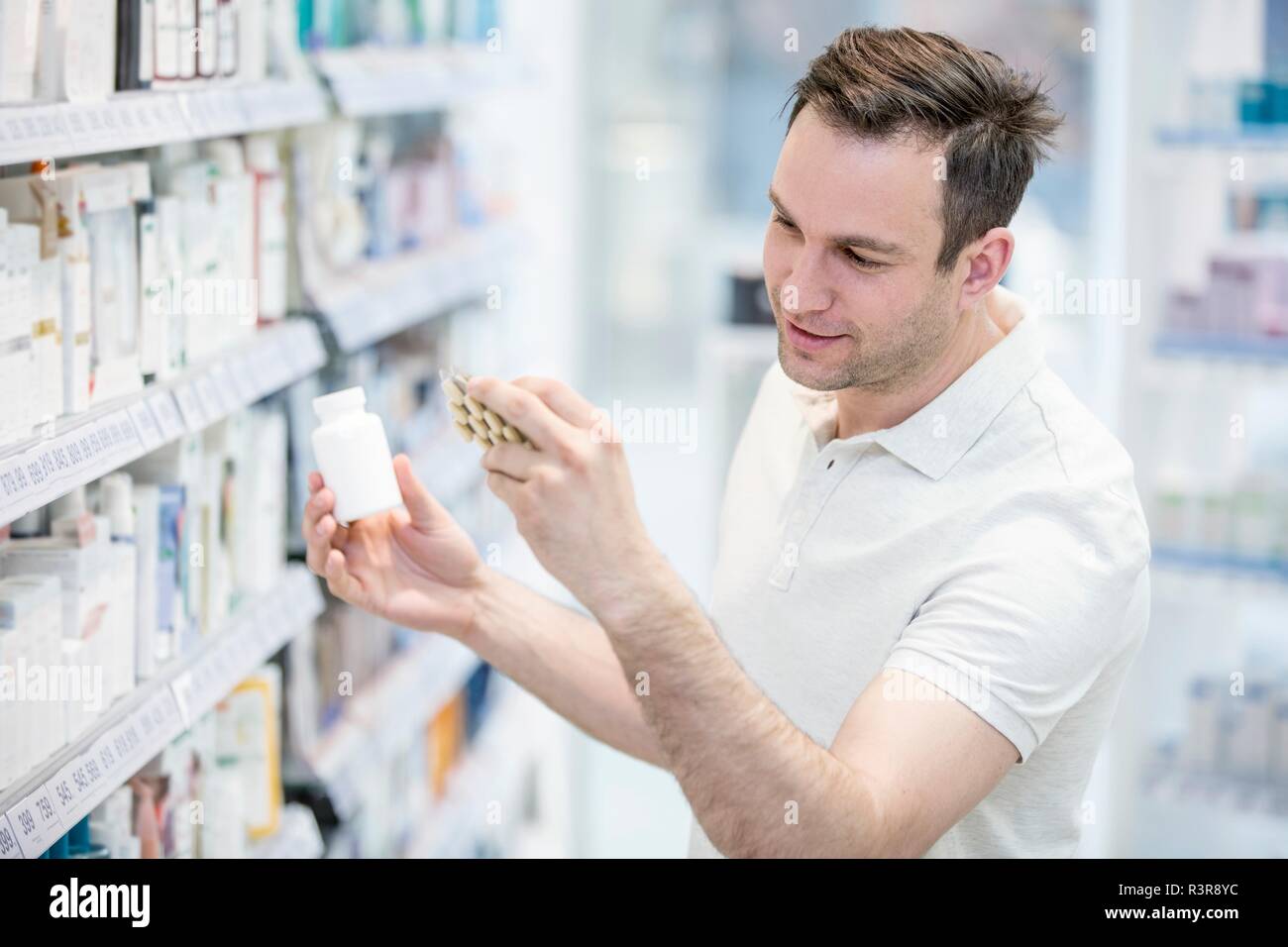 Male customer reading label on comprimé blister en pharmacie. Banque D'Images