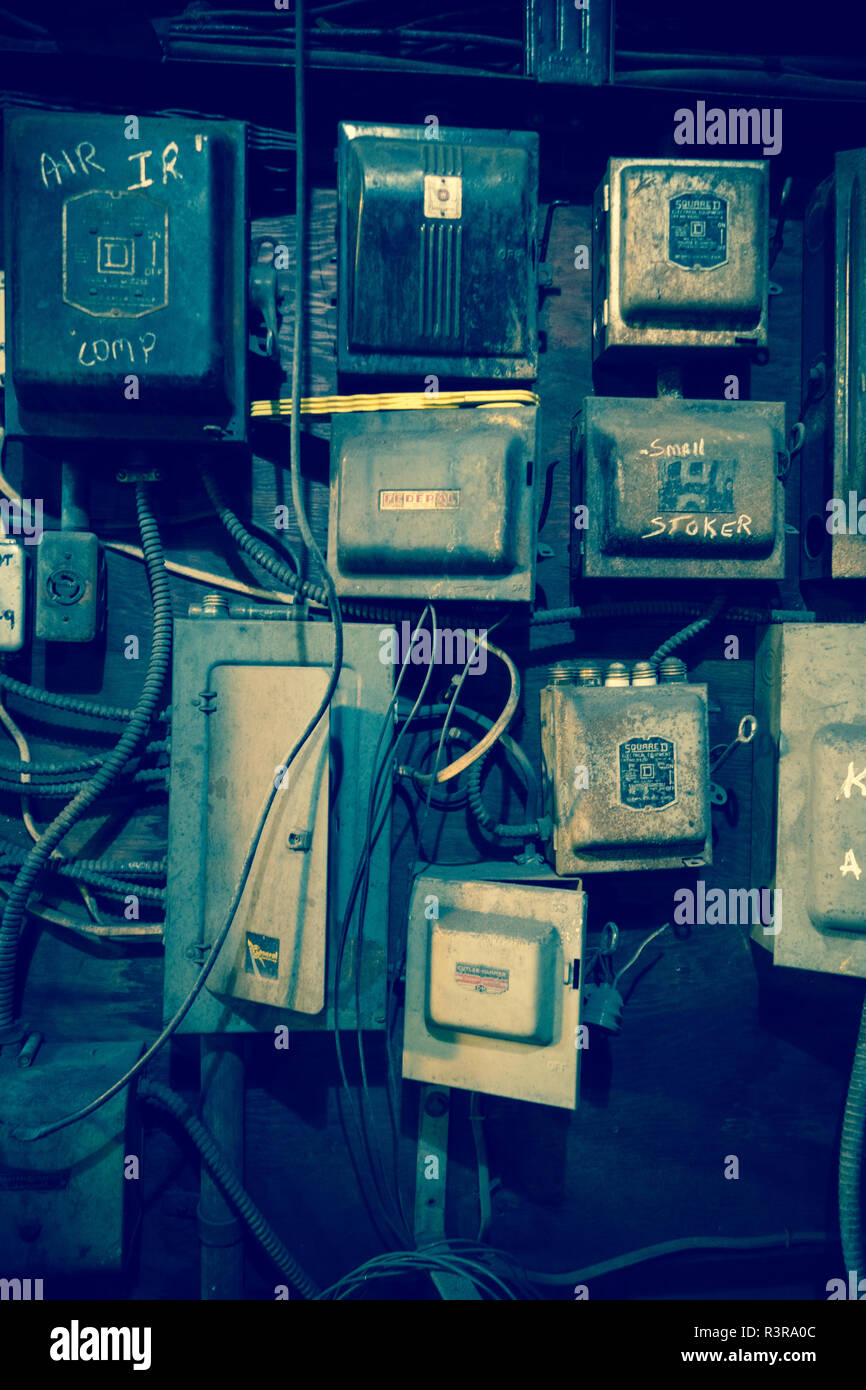Un fouillis de boîtes électriques et fils sont montés ensemble sur un mur, avec un grungy sentir Banque D'Images