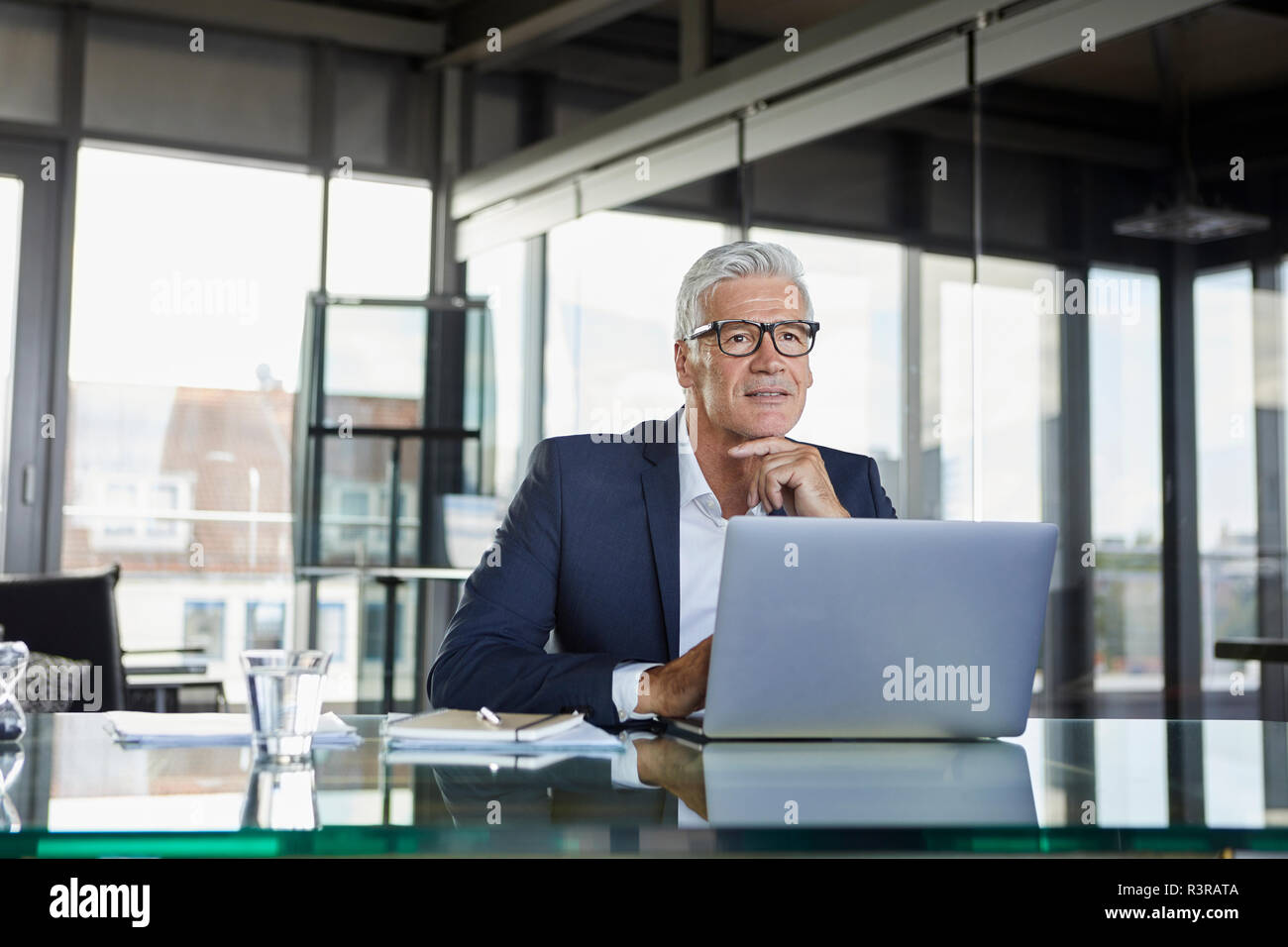 Businessman sitting in office, pensant Banque D'Images