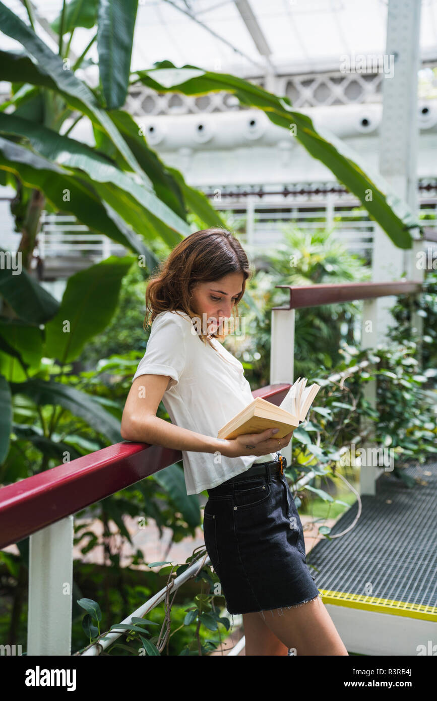 Jeune femme en serre, reading book Banque D'Images