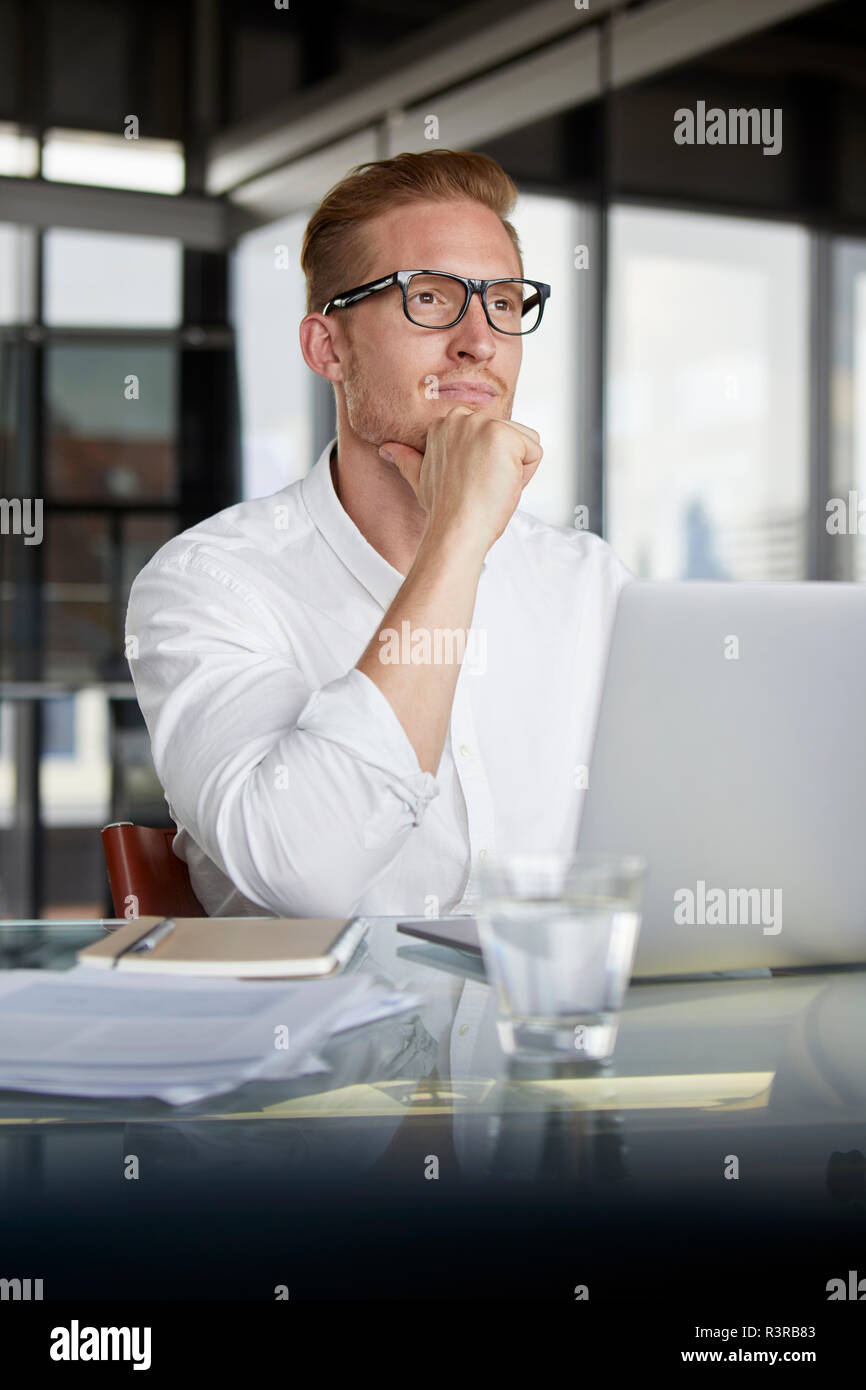 Businessman with laptop on desk in office penser Banque D'Images
