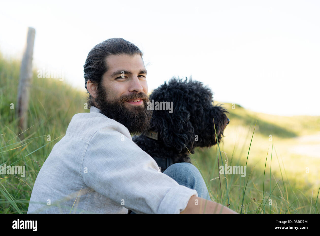 Jeune homme assis dans les dunes avec son chien Banque D'Images Jeune homme assis dans les dunes avec son chien Banque D'Images