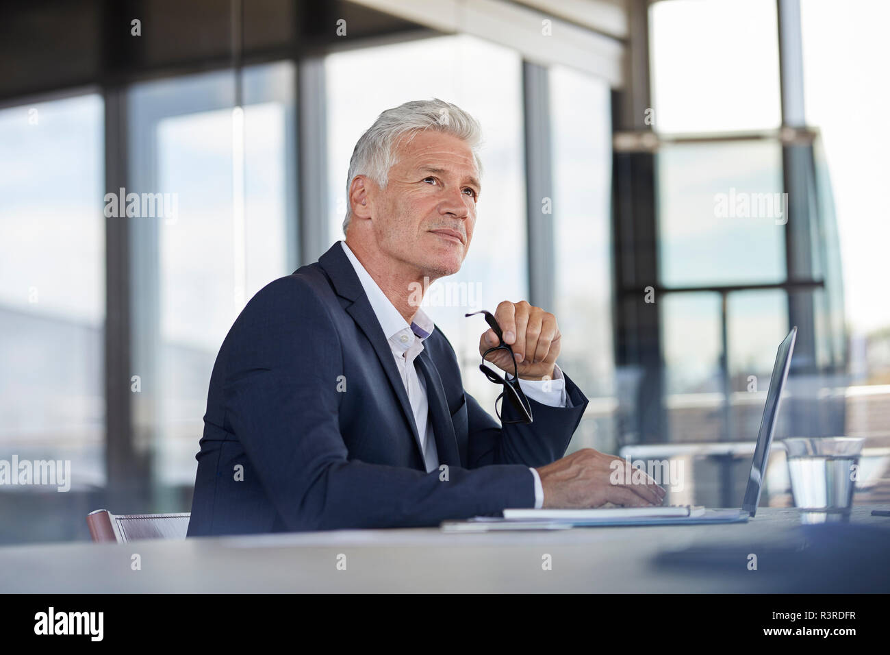 Businessman sitting in office, pensant Banque D'Images