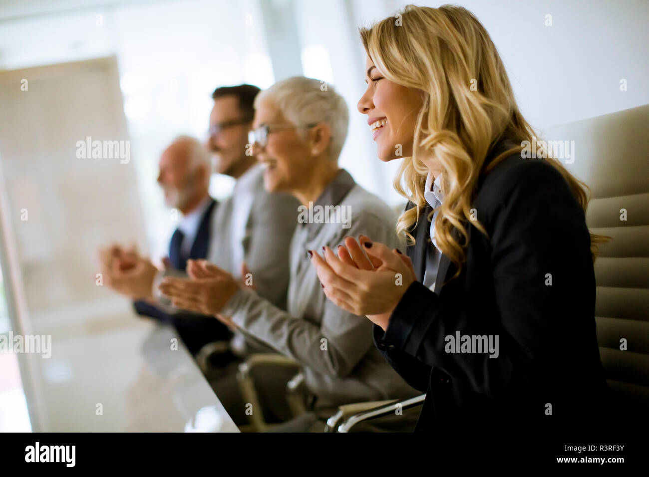 Satisfait de l'équipe entreprises fier clapping hands while sitting in row at office Banque D'Images
