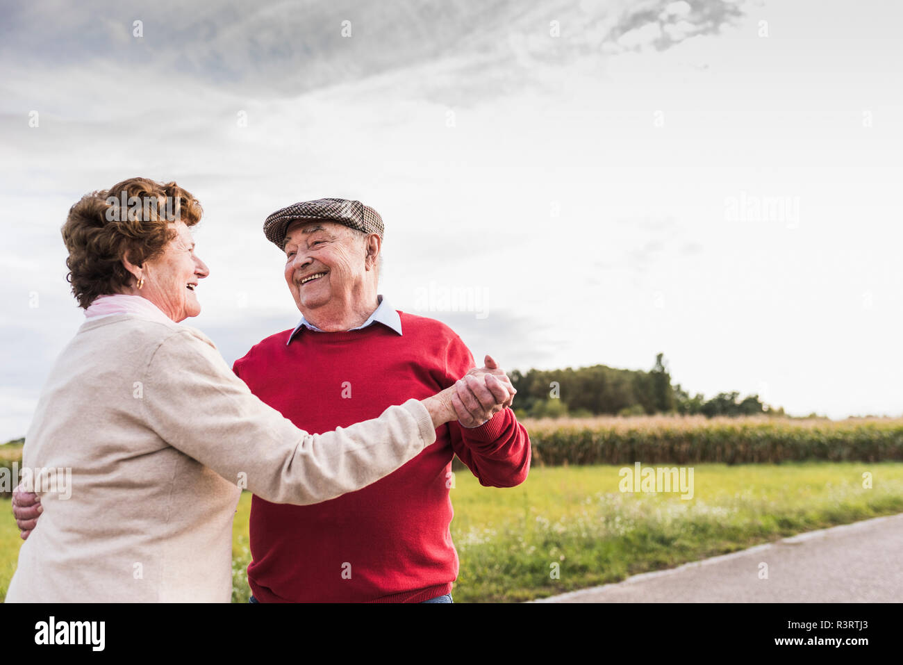 Happy senior couple dancing on country road Banque D'Images