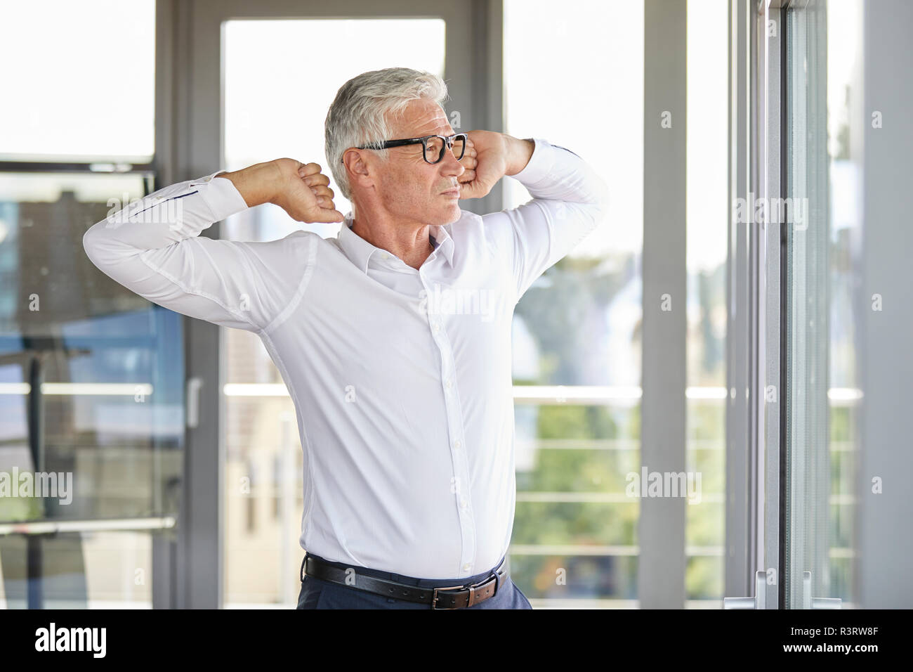 Confident businessman standing in office, s'étendant à la fenêtre Banque D'Images