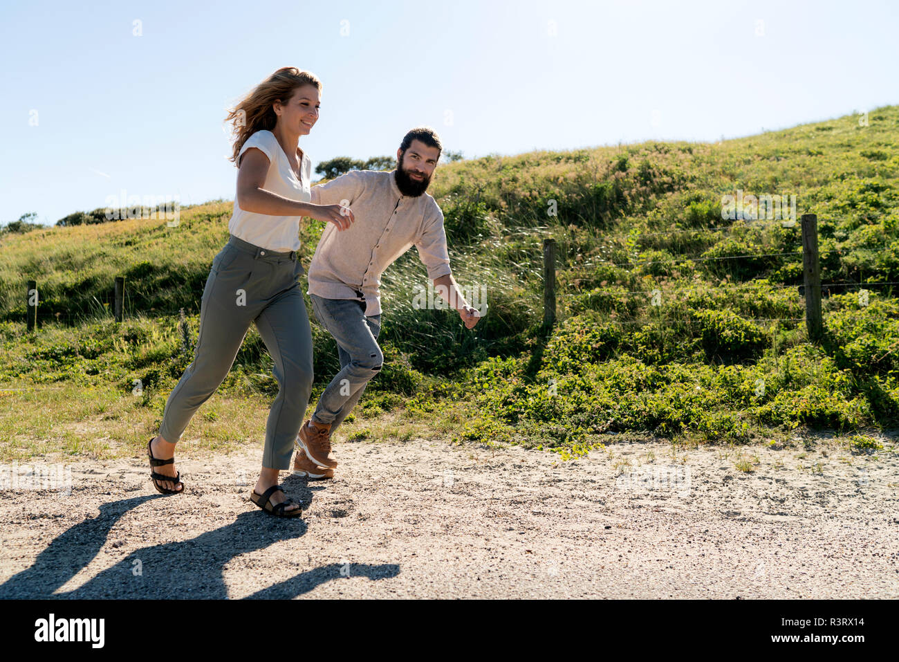 Jeune couple s'amuser dans les dunes, main dans la main courante Banque D'Images Jeune couple s'amuser dans les dunes, main dans la main courante Banque D'Images
