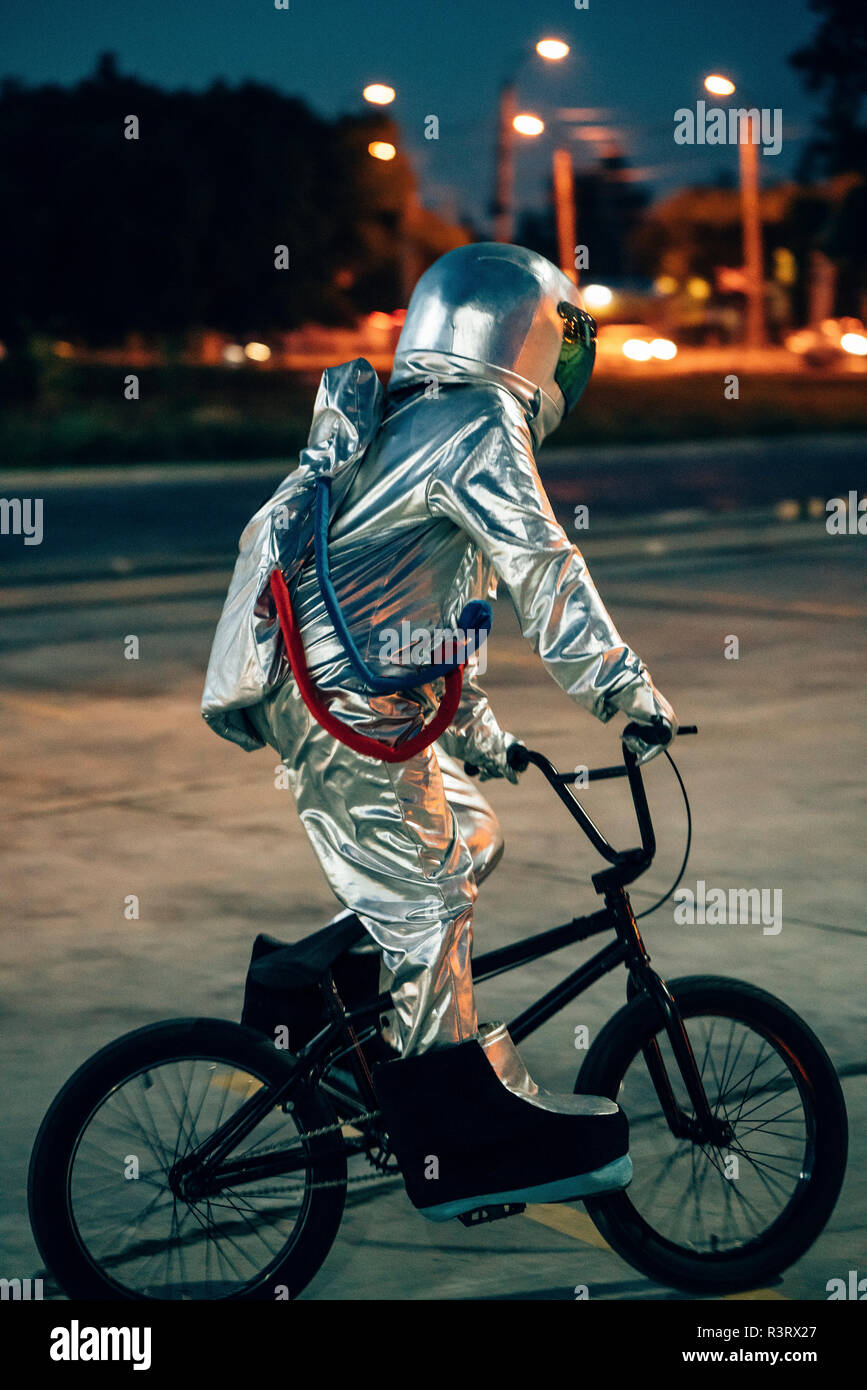 Spaceman dans la ville la nuit sur parking équitation vélo BMX Banque D'Images