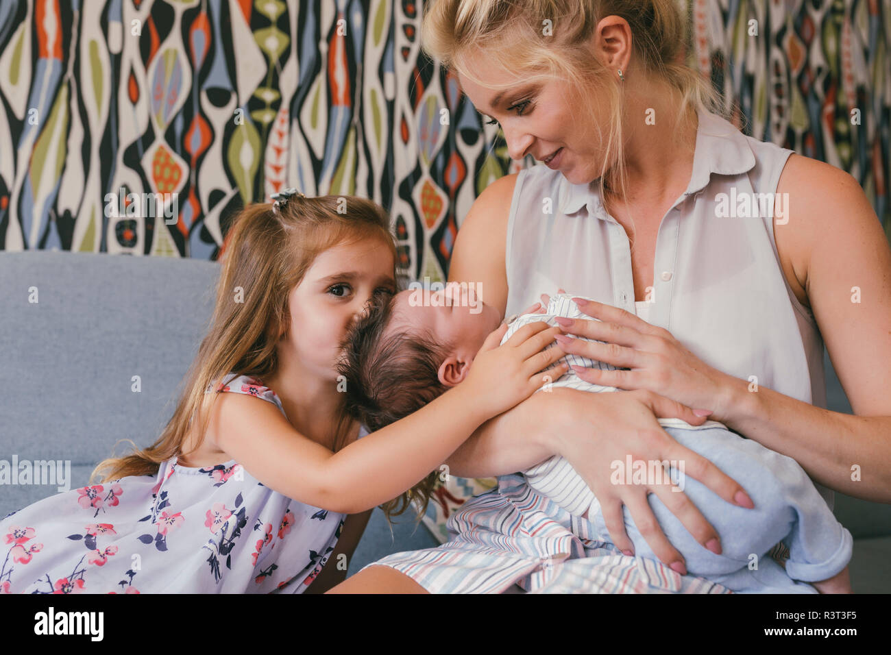 Smiling mother sitting on couch avec nouveau-né et sa fille Banque D'Images