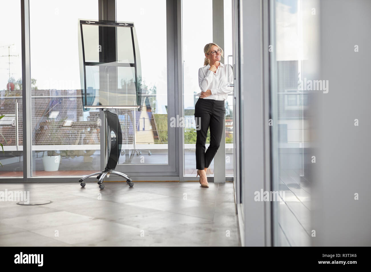 Successful businessman standing in office, à la fenêtre de Banque D'Images