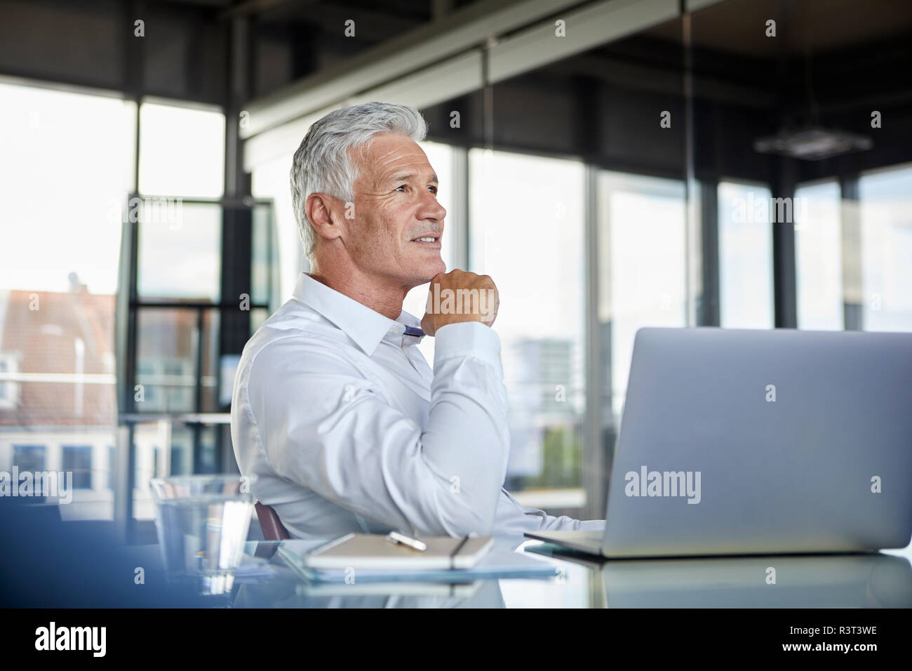 Businessman sitting in office, pensant Banque D'Images