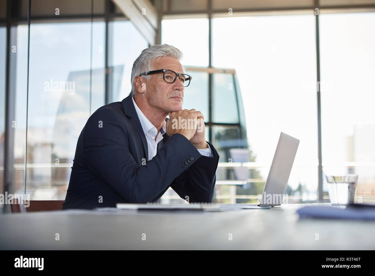 Businessman sitting in office, pensant Banque D'Images