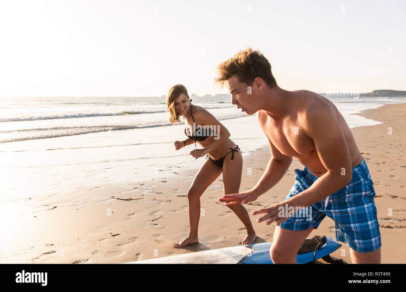 Jeune homme jeune femme montrant comment surfer sur la plage Banque D'Images