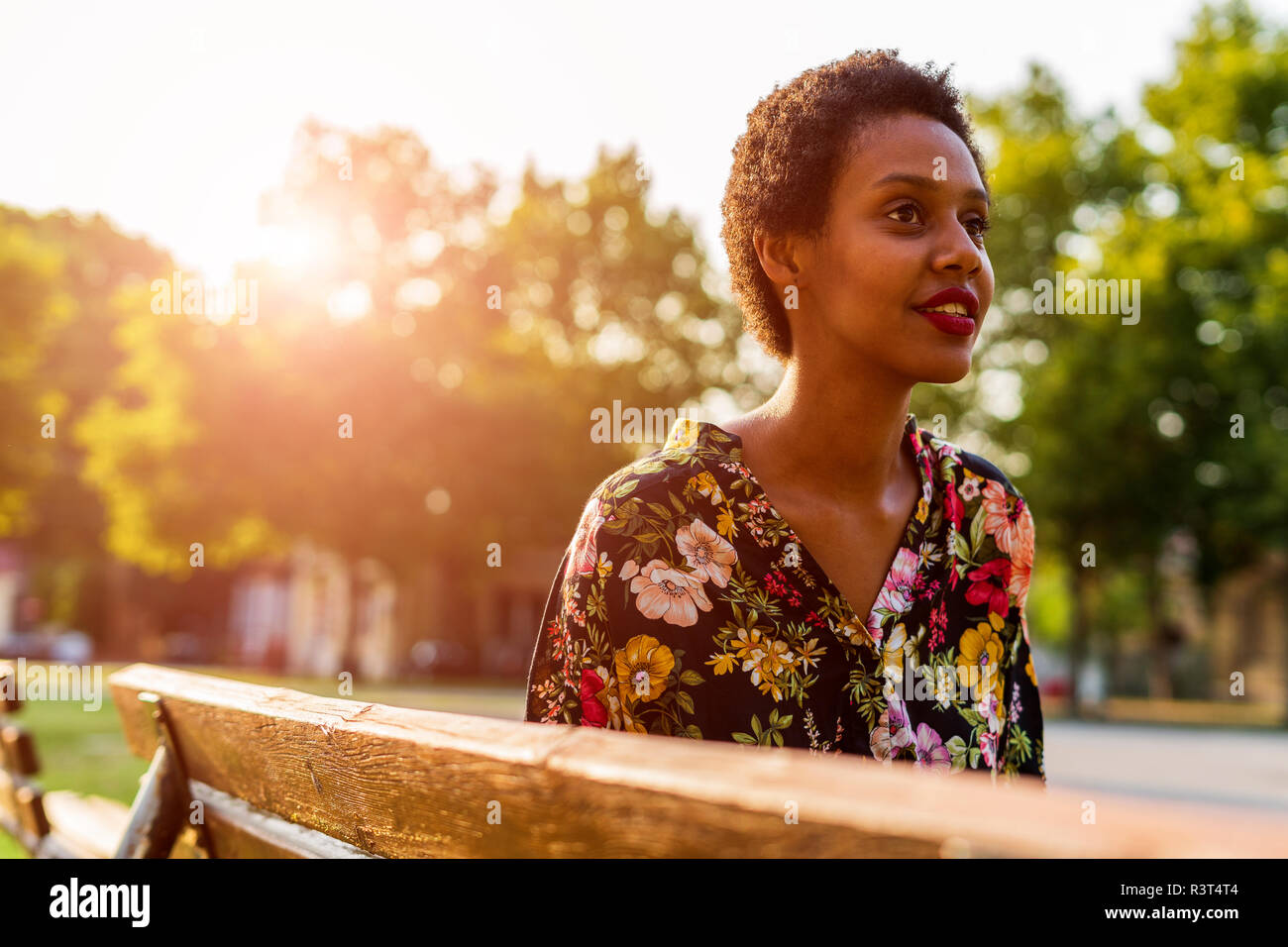 Jeune femme sur un banc dans un parc au coucher du soleil Banque D'Images