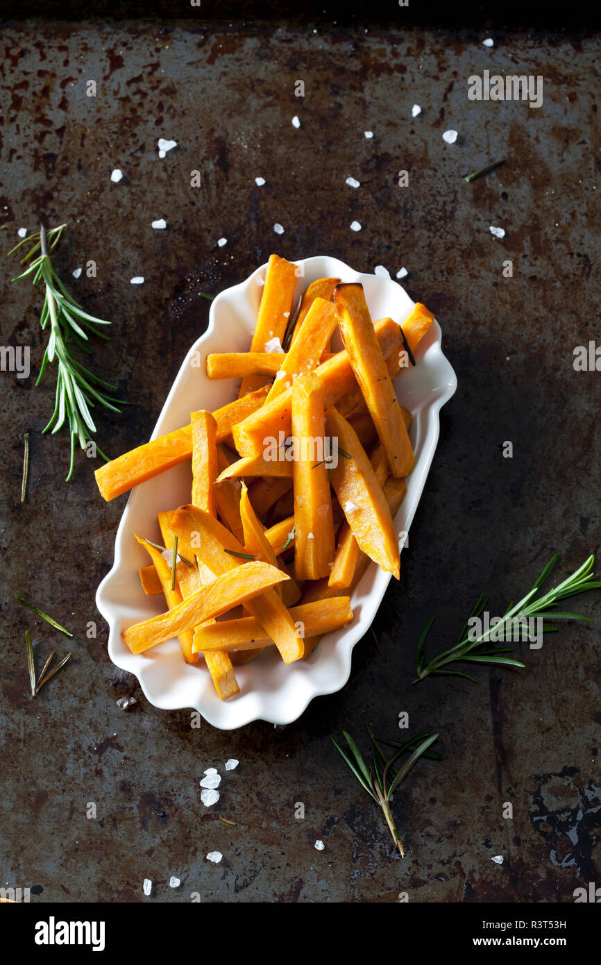 Frites de patates douces avec romarin et sel dans un bol en porcelaine Banque D'Images