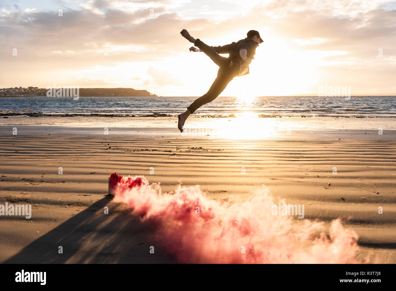 Homme formation mouvement à la plage avec la fumée colorée au coucher du soleil Banque D'Images