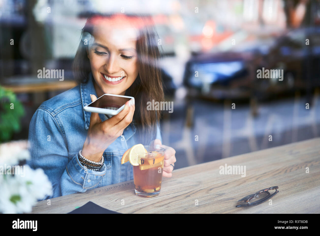 Jeune femme parlant au téléphone dans un café tout en prenant le thé Banque D'Images