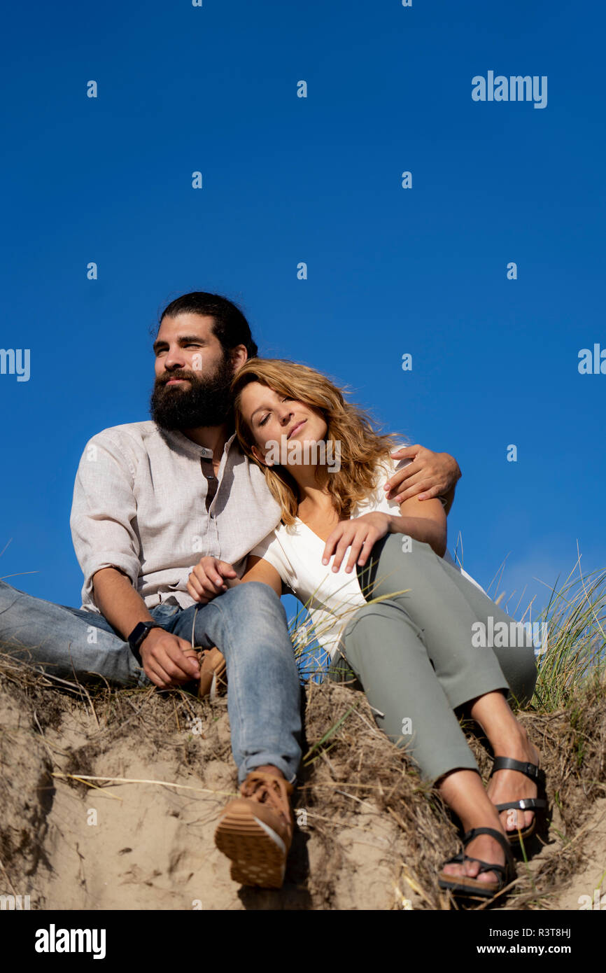Jeune couple assis sur une dune en été, détente Banque D'Images Jeune couple assis sur une dune en été, détente Banque D'Images