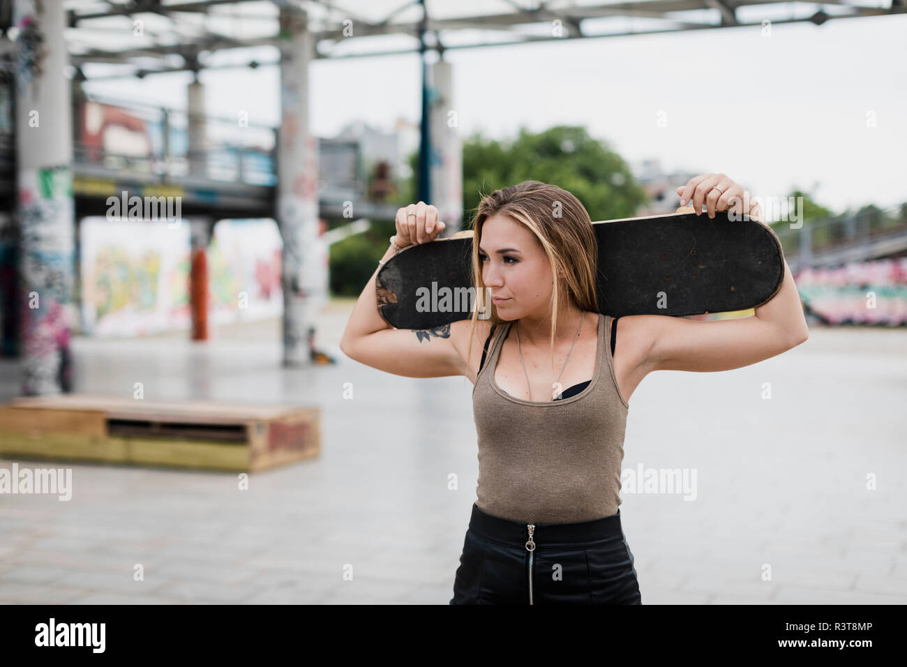 Cool young woman carrying skateboard dans la ville Banque D'Images