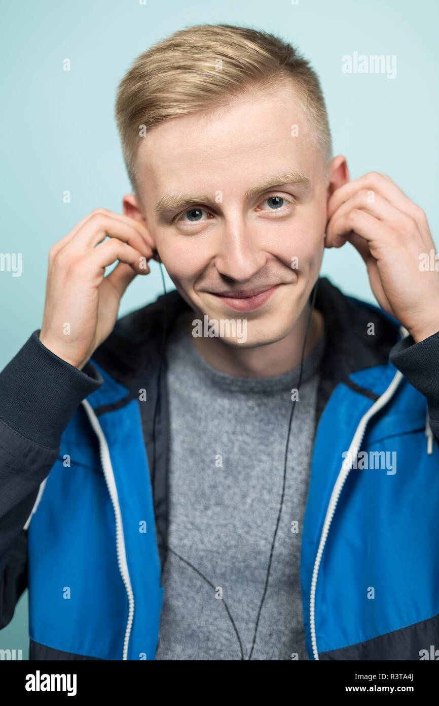 Portrait of smiling young man putting on earphones Banque D'Images