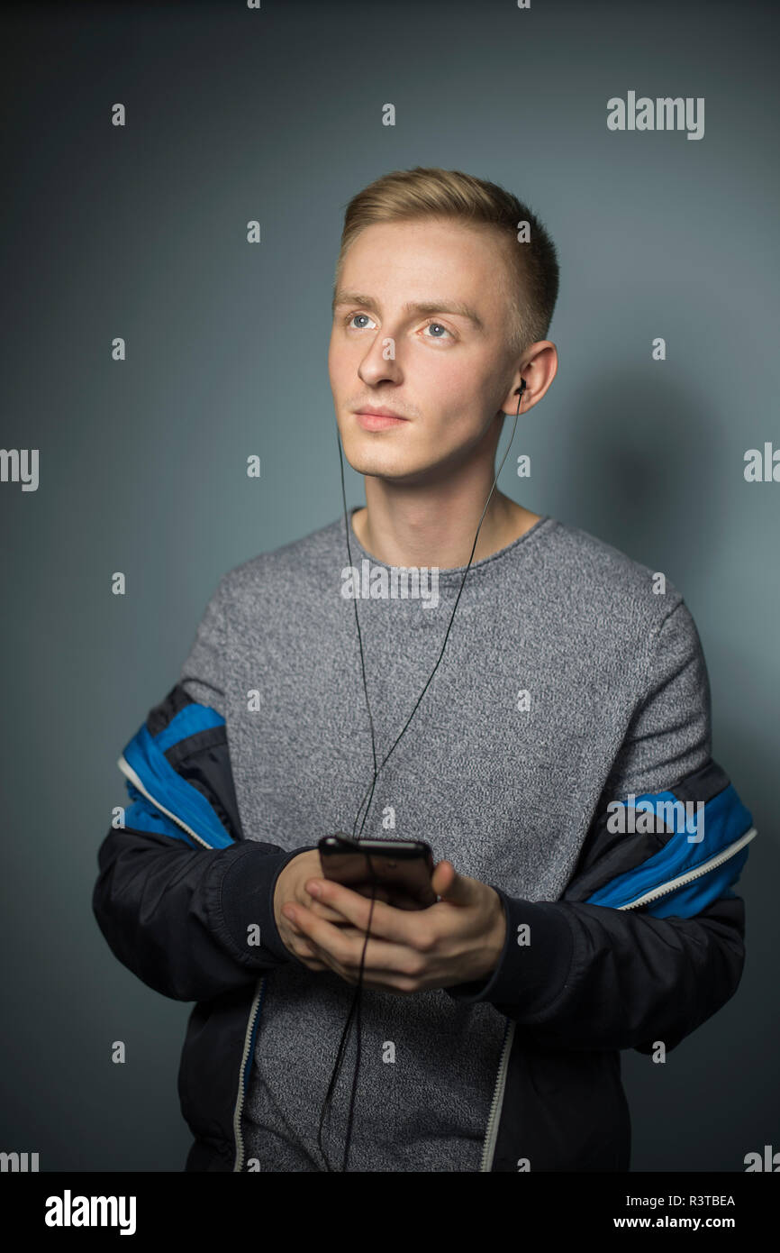 Portrait de jeune homme à l'écoute de la musique avec des écouteurs et smartphone Banque D'Images