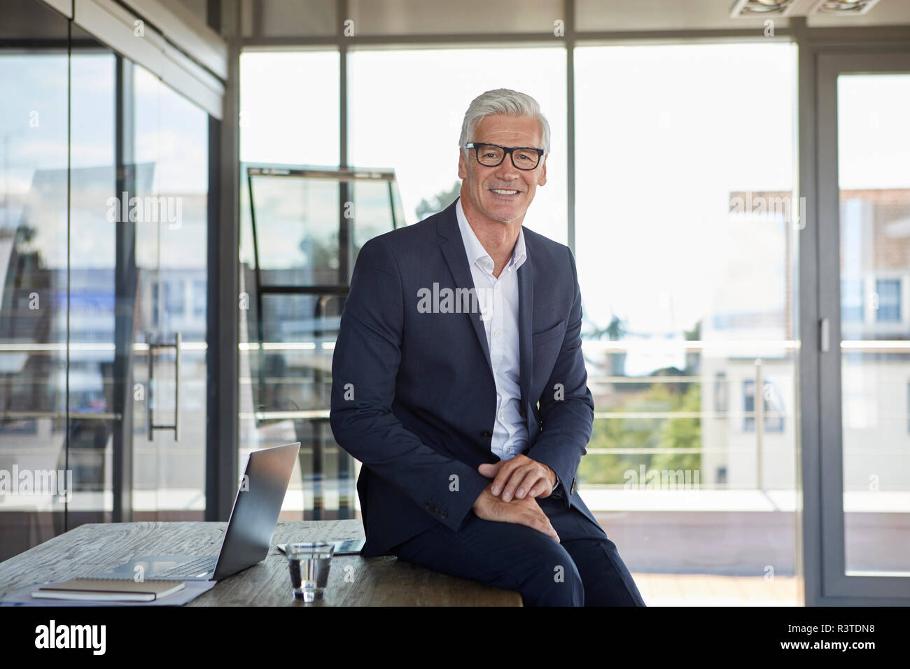 Gestionnaire réussie sitting on desk, smiling Banque D'Images