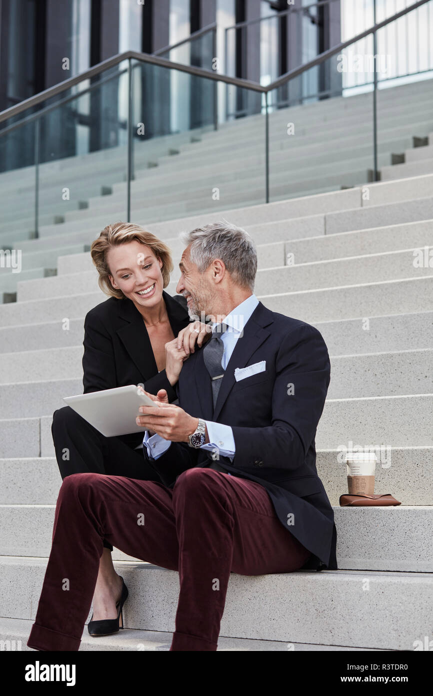 Deux smiling business people avec tablet sitting on stairs Banque D'Images