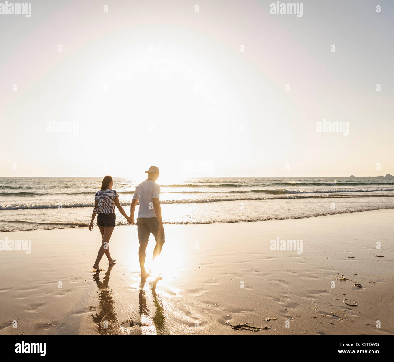 Jeune couple faisant une promenade de plage romantique au coucher du soleil Banque D'Images