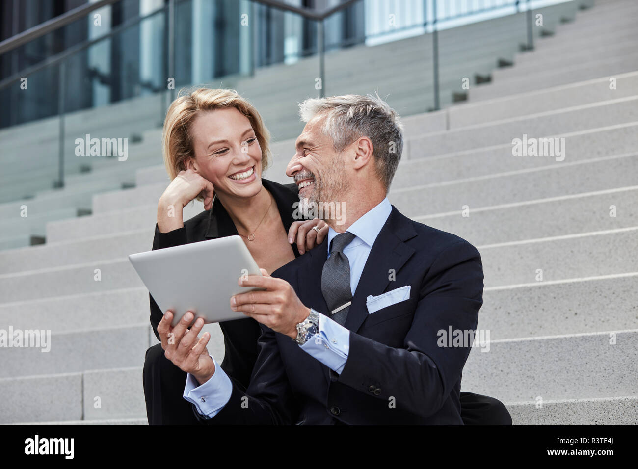 Portrait de deux de rire des gens d'affaires avec tablet assis ensemble sur des escaliers Banque D'Images