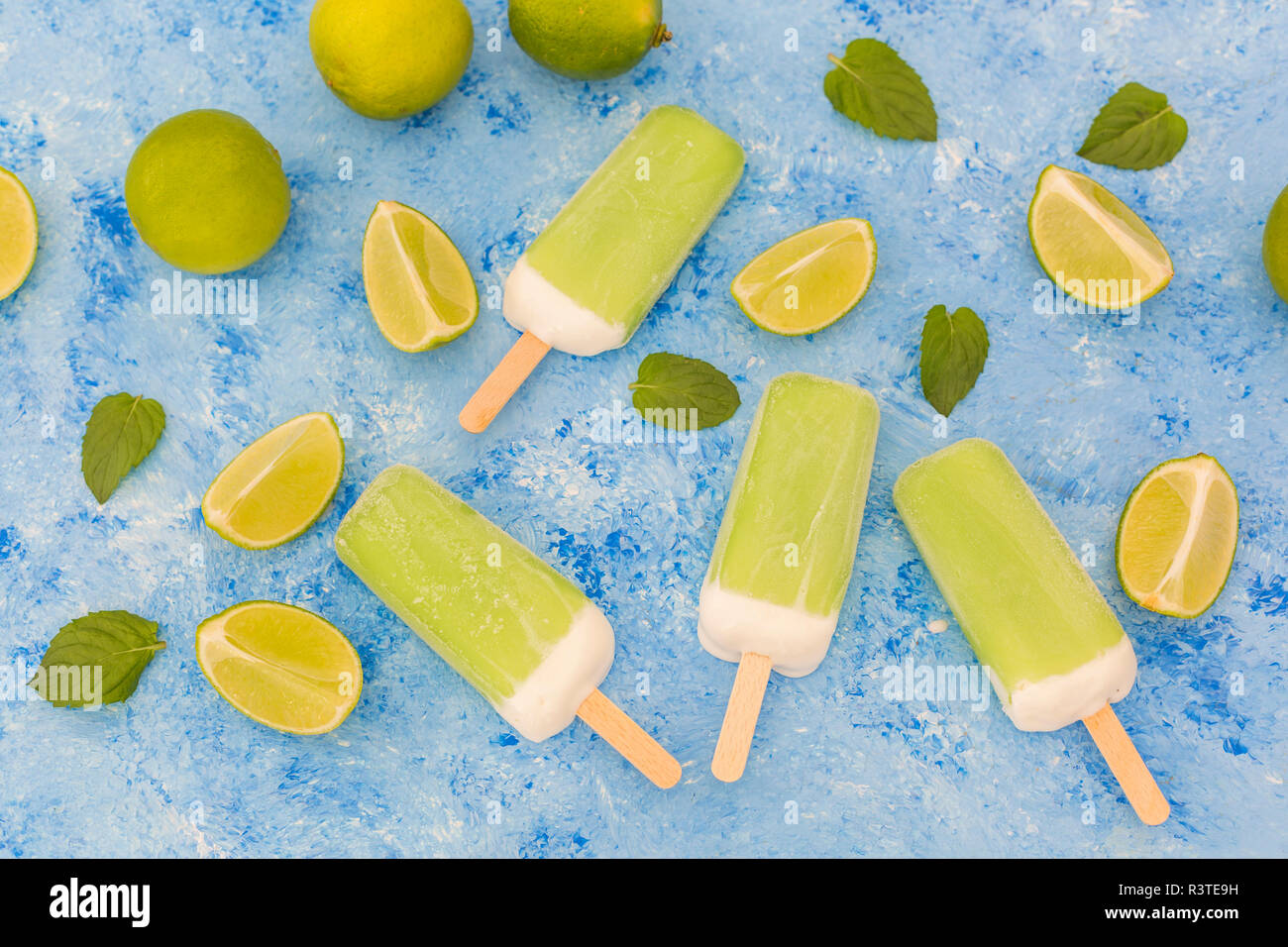 Sucettes glacées à la menthe citron vert, des limes et des feuilles de menthe sur fond bleu clair Banque D'Images