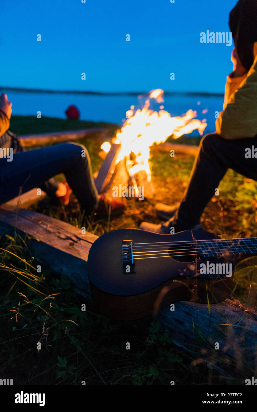 Les amis assis à un feu de camp, à regarder les flammes Banque D'Images