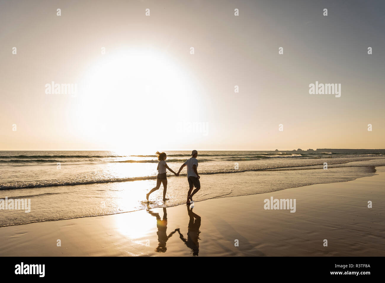 Jeune couple faisant une promenade de plage romantique au coucher du soleil Banque D'Images