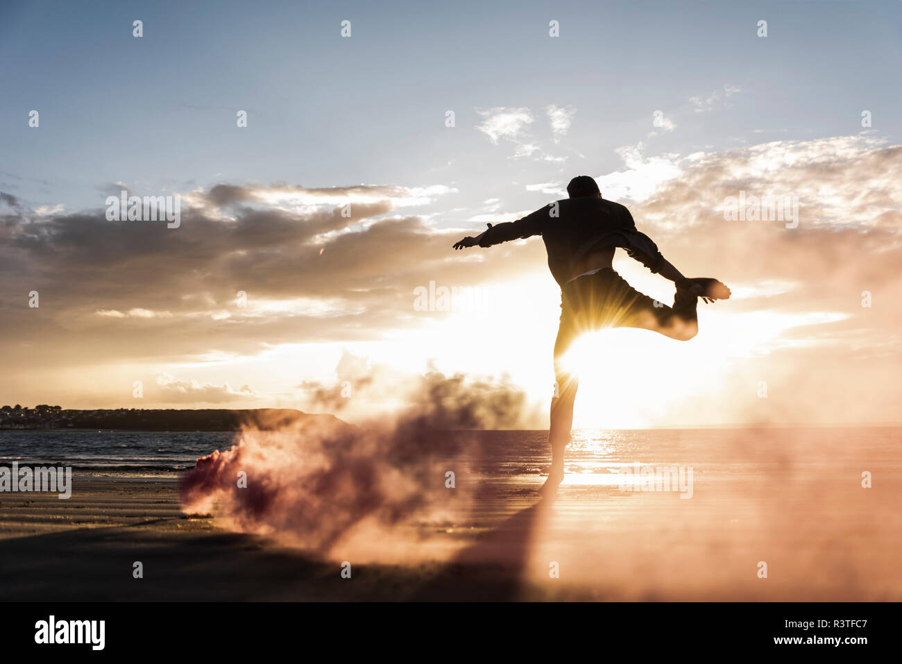 Homme formation mouvement à la plage avec la fumée colorée au coucher du soleil Banque D'Images