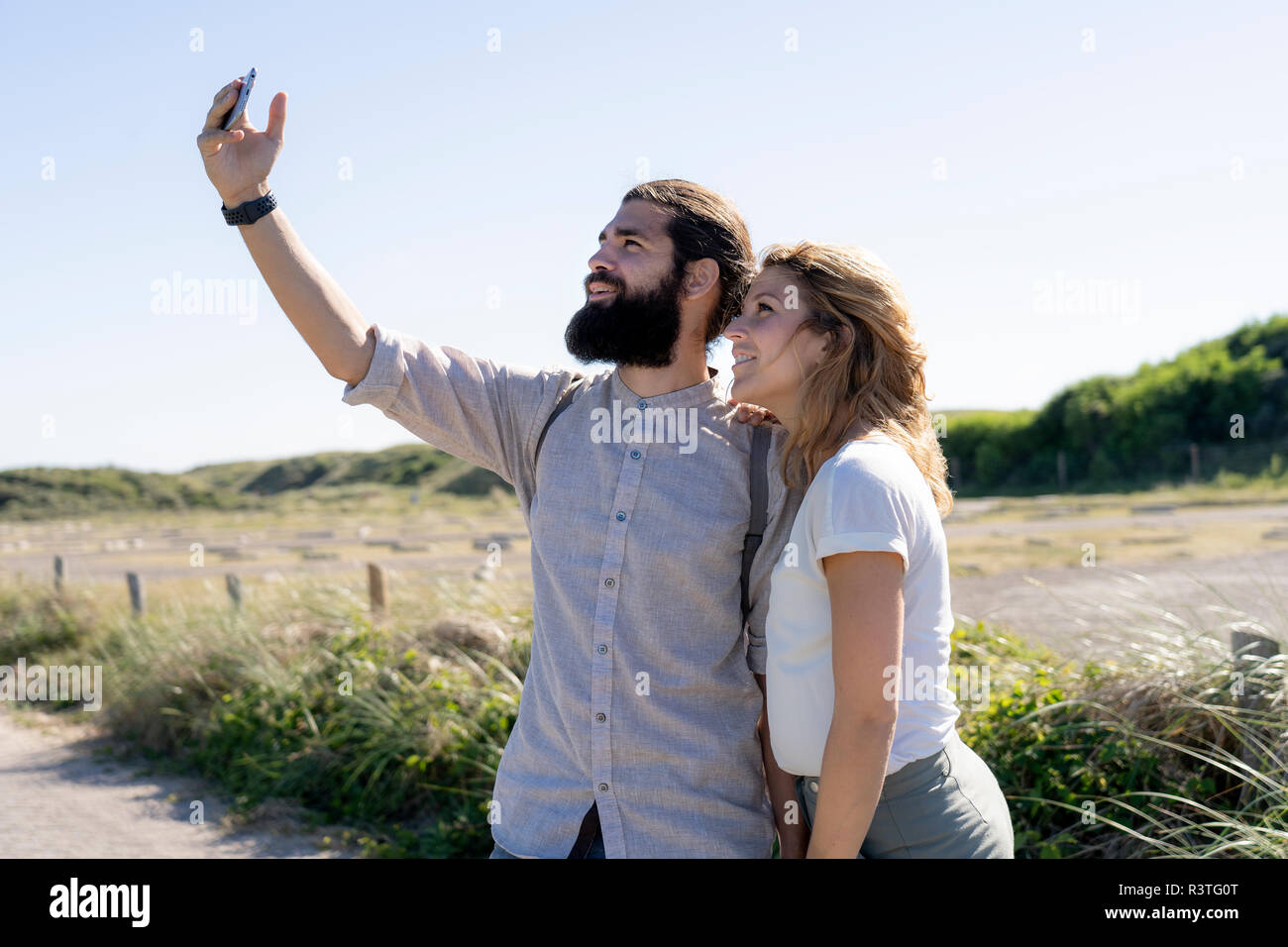 Jeune couple en tenant vos autoportraits smartphone sur la plage Banque D'Images