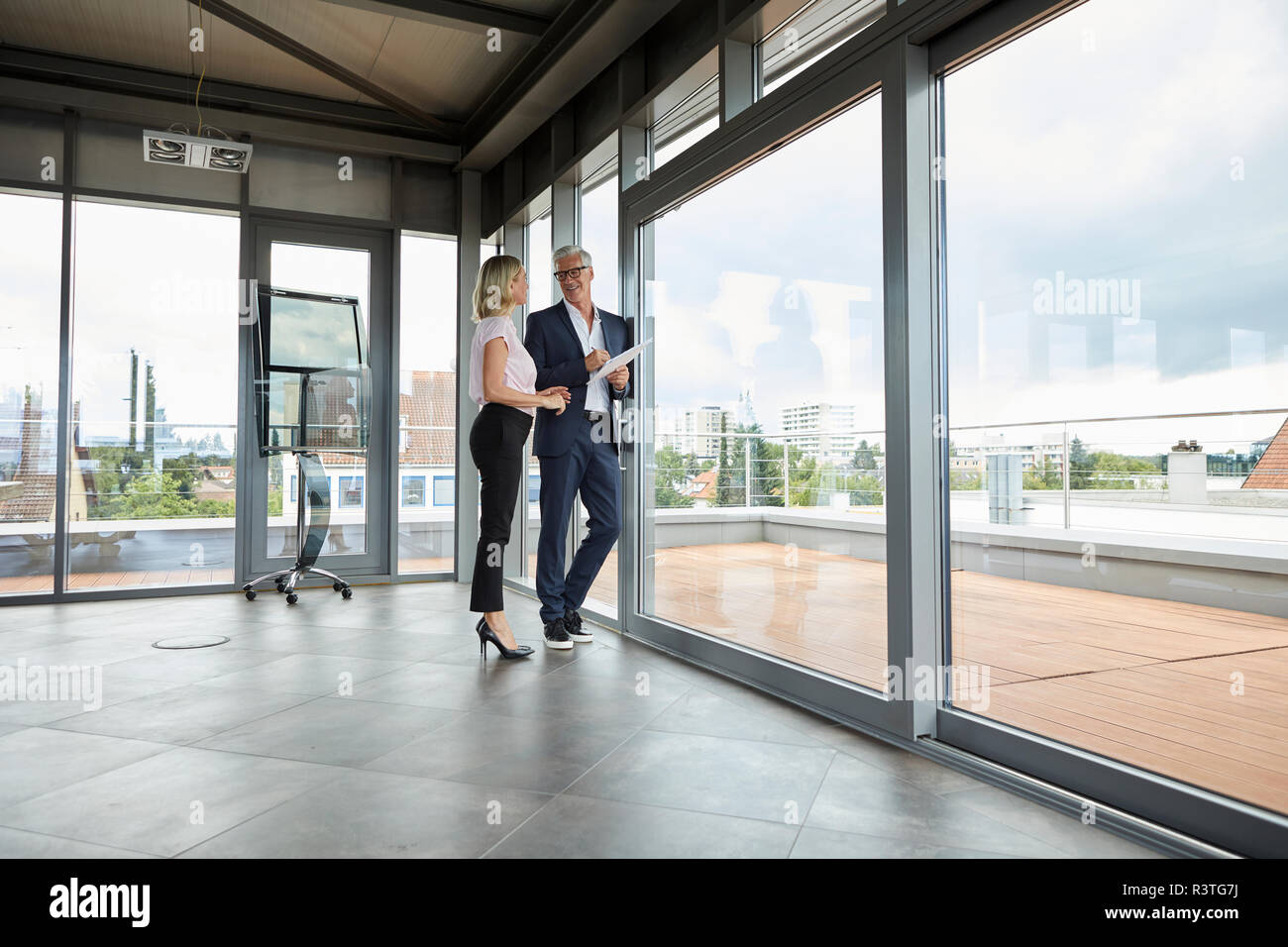 Businessman and woman standing in office, discuter de projet, holding documents Banque D'Images