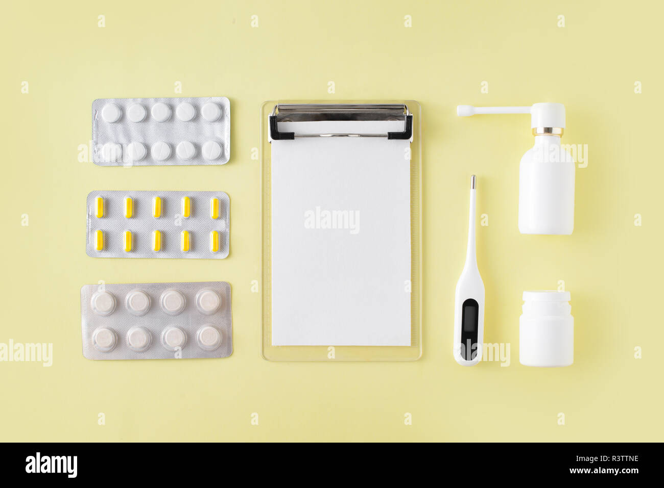 Comprimés, thermomètre et remarque pour la recette sur fond jaune. Le traitement du rhume et de la grippe. Mise à plat, vue du dessus. Banque D'Images