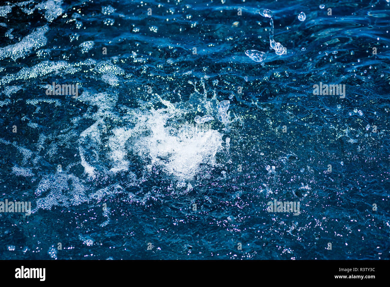 Les projections d'eau et les gouttelettes sur la surface bleue Banque D'Images