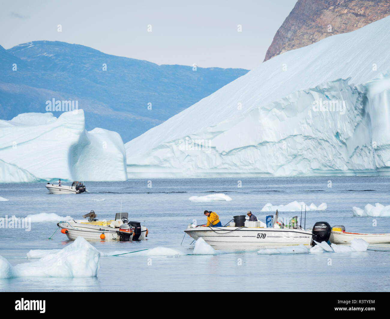 Port avec bateaux de pêche typiques entre les icebergs. Petite ville d'Uummannaq dans le nord-ouest du Groenland, le Danemark (usage éditorial uniquement) Banque D'Images
