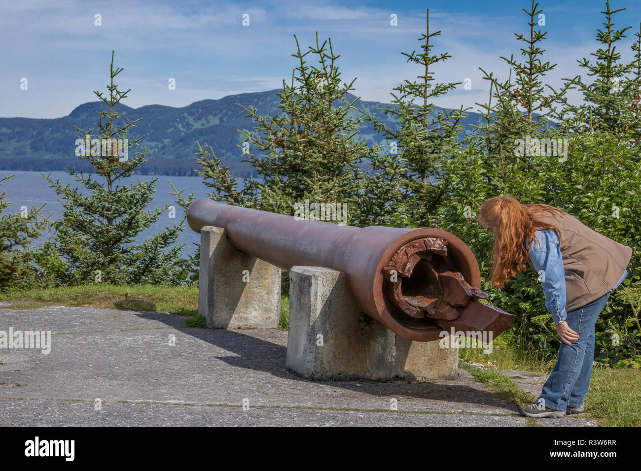 USA, Alaska, Kodiak. Woman inspecting un canon de 8 pouces à partir de la DEUXIÈME GUERRE MONDIALE, au point d'artillerie Miller à Fort Abercrombie. (MR) Banque D'Images