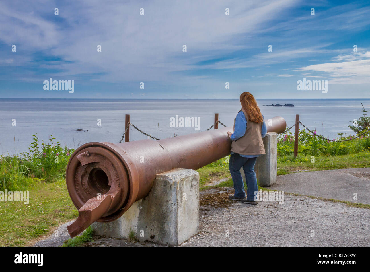 USA, Alaska, Kodiak. Femme profitant de la vue depuis un point Miller 8 pouces canon d'artillerie de la SECONDE GUERRE MONDIALE à Fort Abercrombie. (MR) Banque D'Images