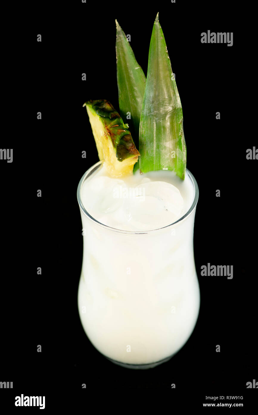 Pina Colada cocktail avec le jus d'ananas, rhum blanc et crème de coco ananas décoré de feuilles et de fruits isolés avec fond noir Banque D'Images