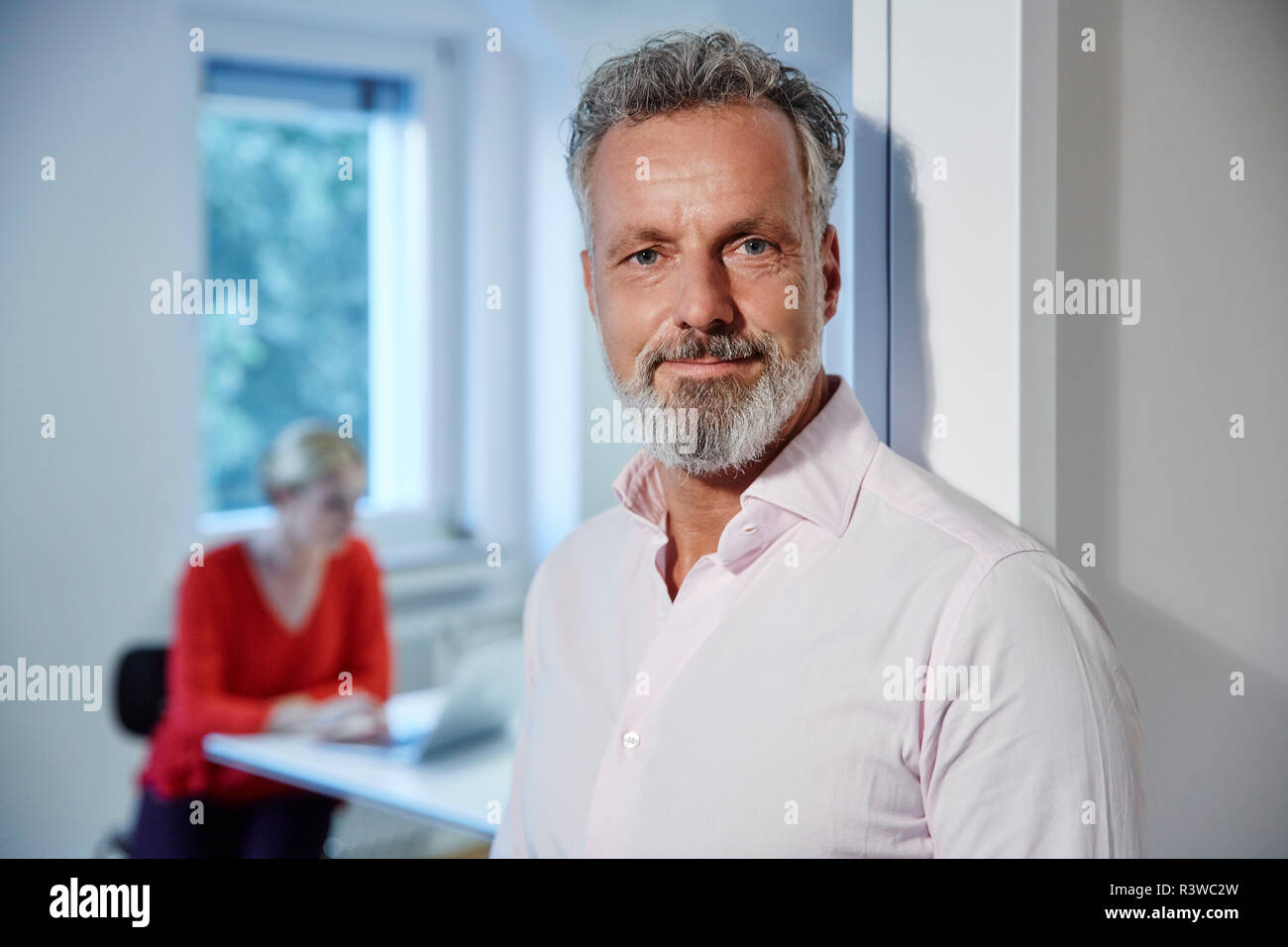 Portrait of mature man ln bureau avec collègue en arrière-plan Banque D'Images