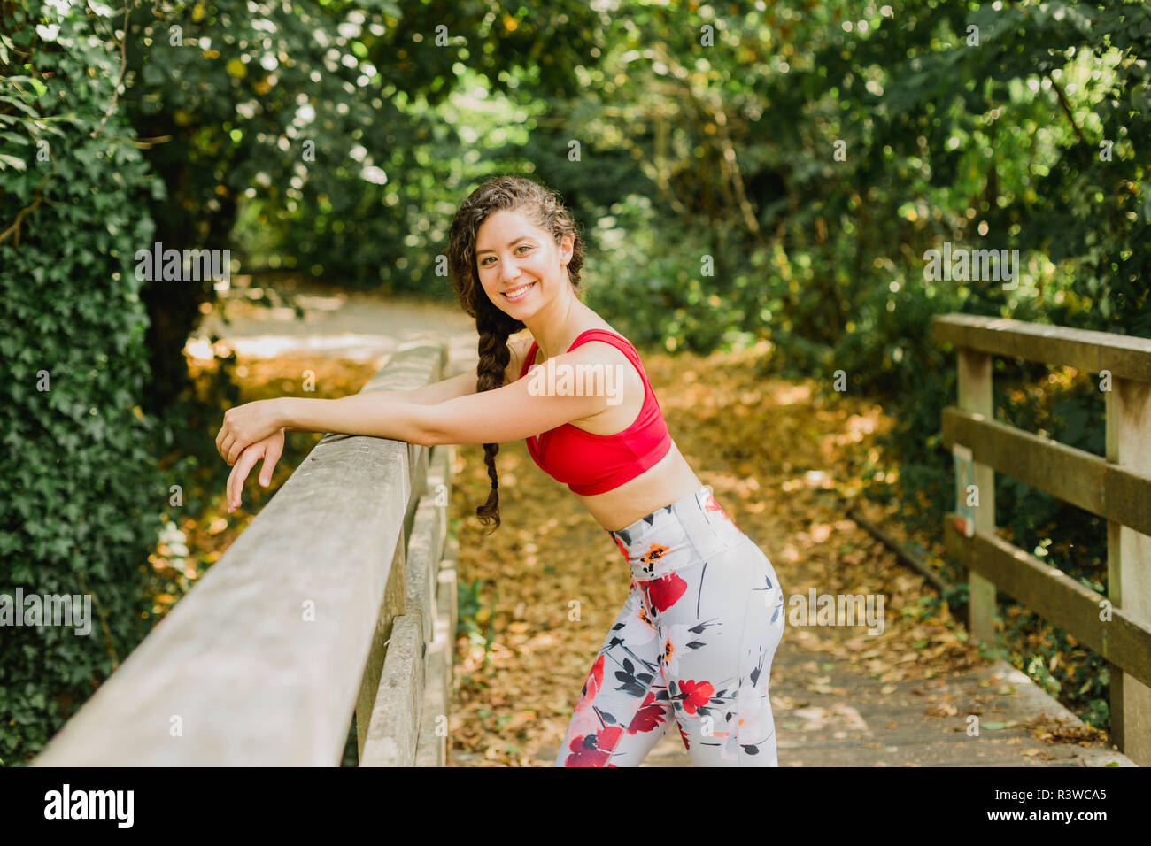 Young woman smiling pendant les pauses, après avoir pratiqué la méthode Pilates dans un parc urbain Banque D'Images