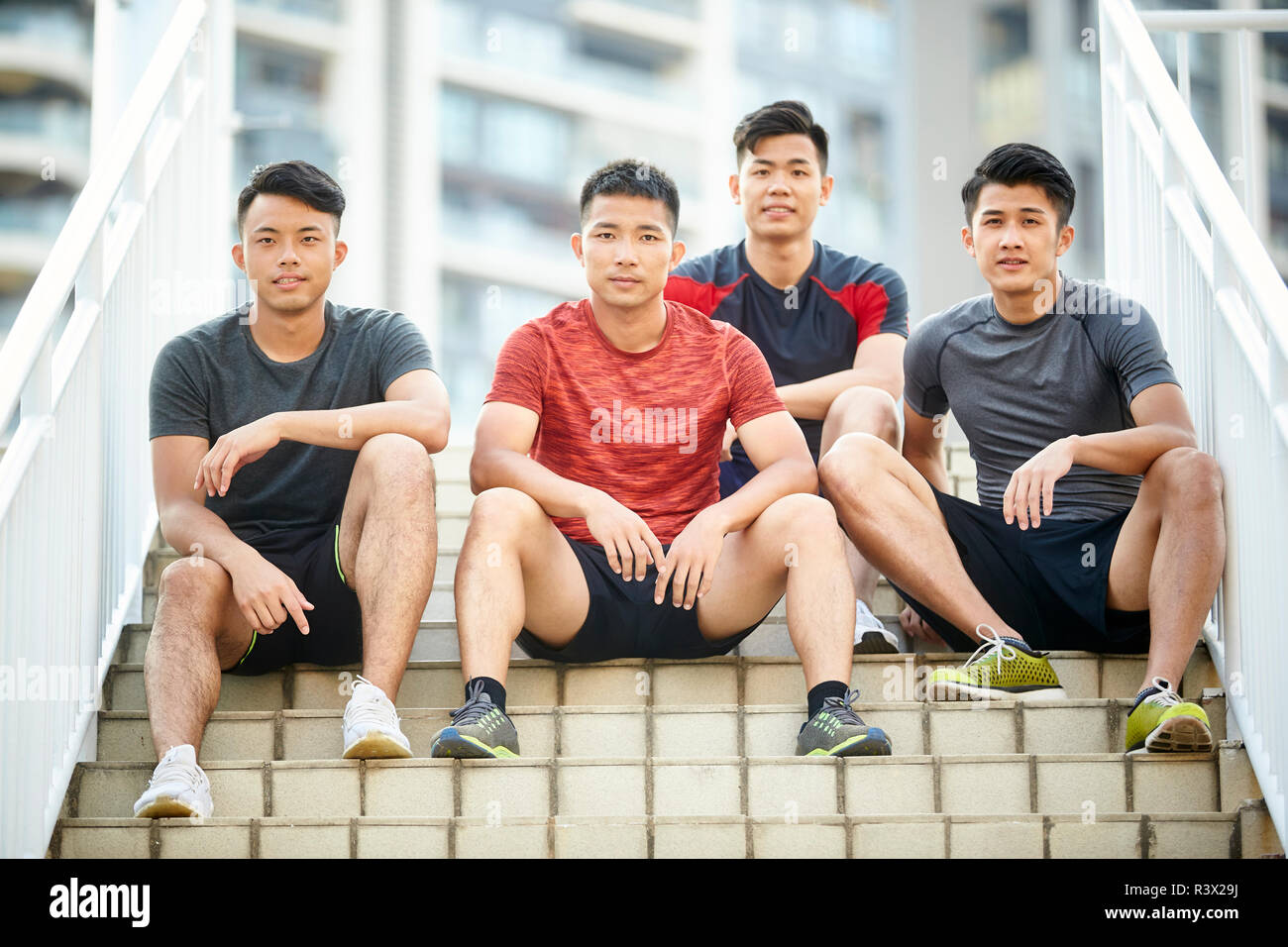 Portrait en extérieur d'une équipe de quatre jeunes athlètes asiatiques sitting on steps Banque D'Images
