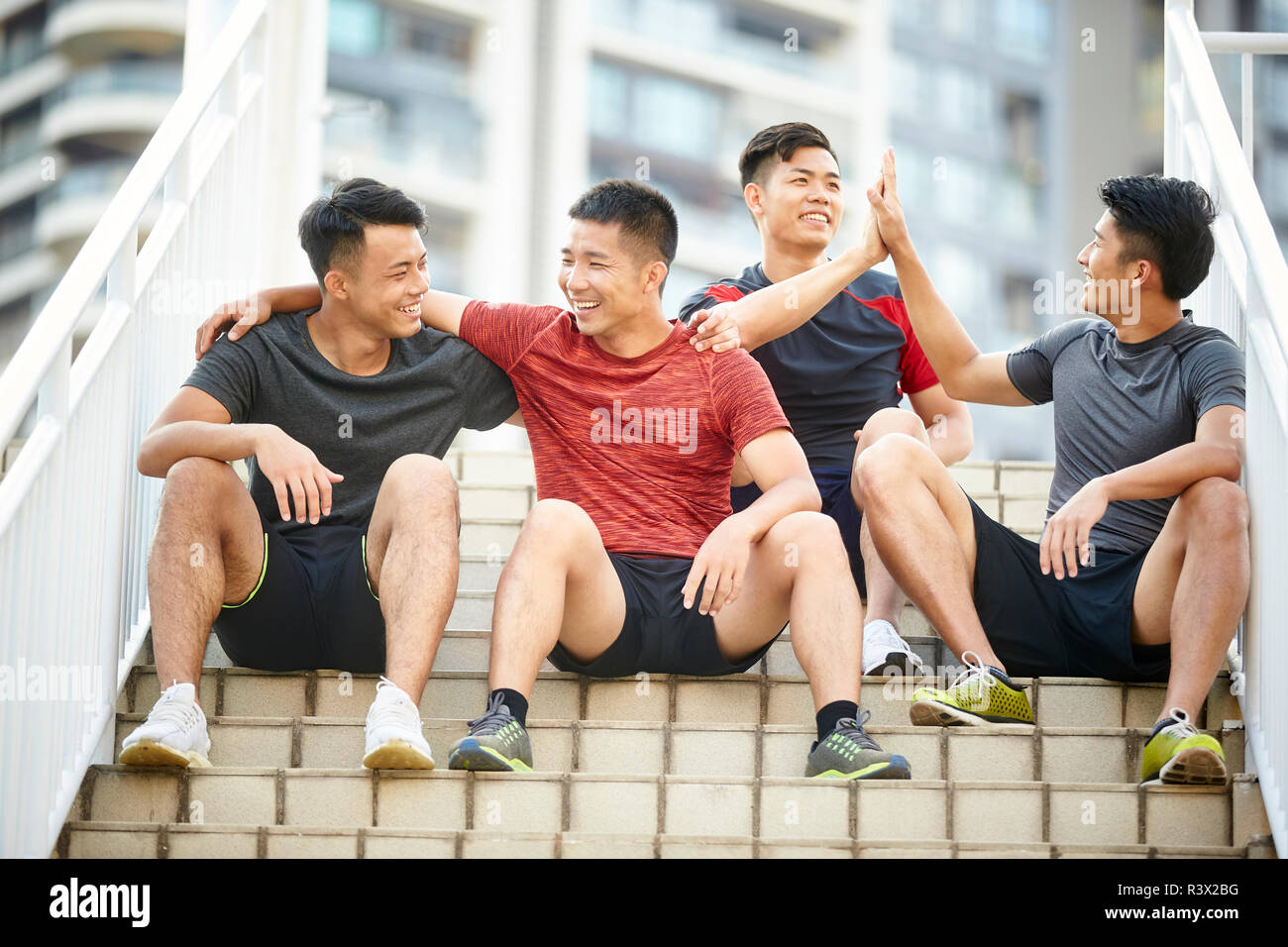 Portrait en extérieur d'une équipe de quatre jeunes athlètes asiatiques sitting on steps Banque D'Images