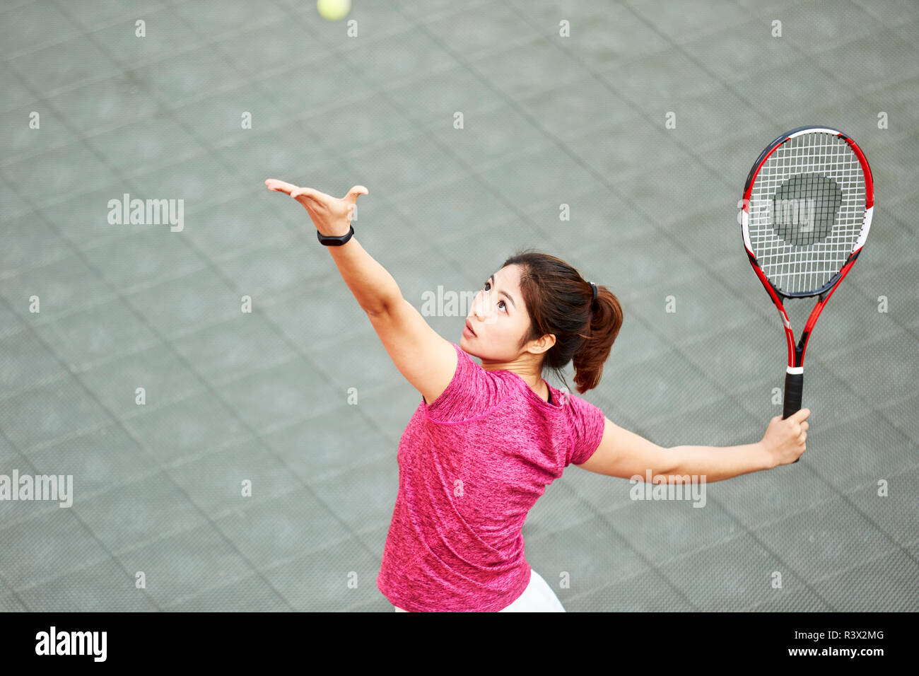 Young Asian tennis player servant dans match Banque D'Images